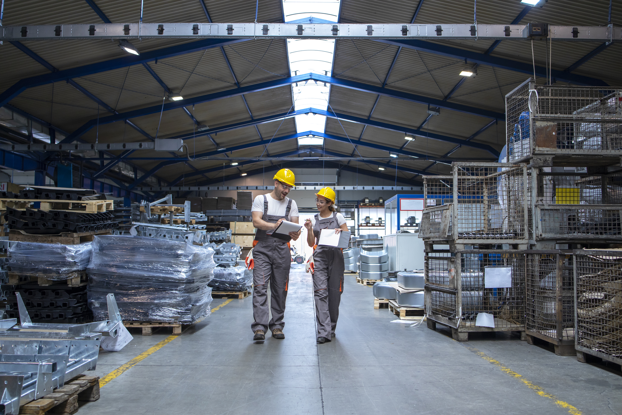 Factory workers walking through large production hall and having conversation.