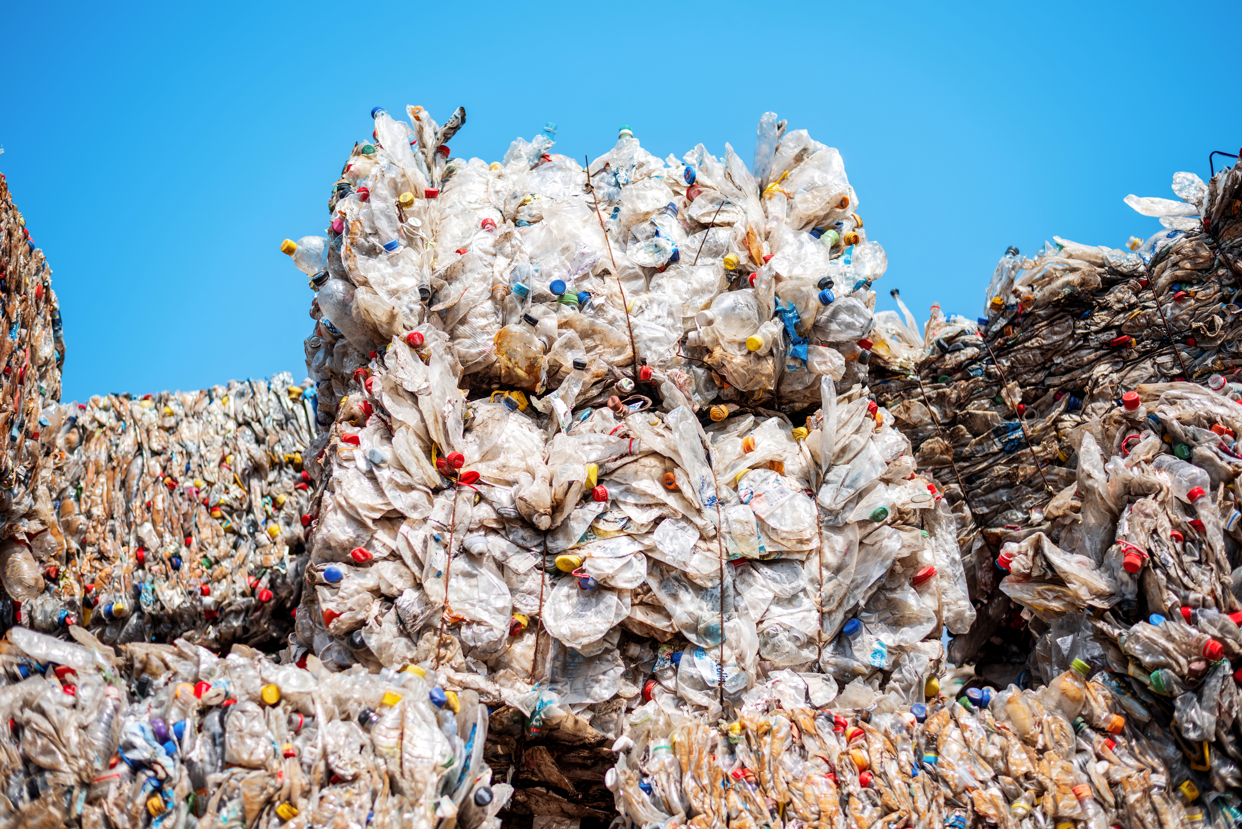 Multiple cubes of compressed plastic garbage near the waste recycling factory in open air